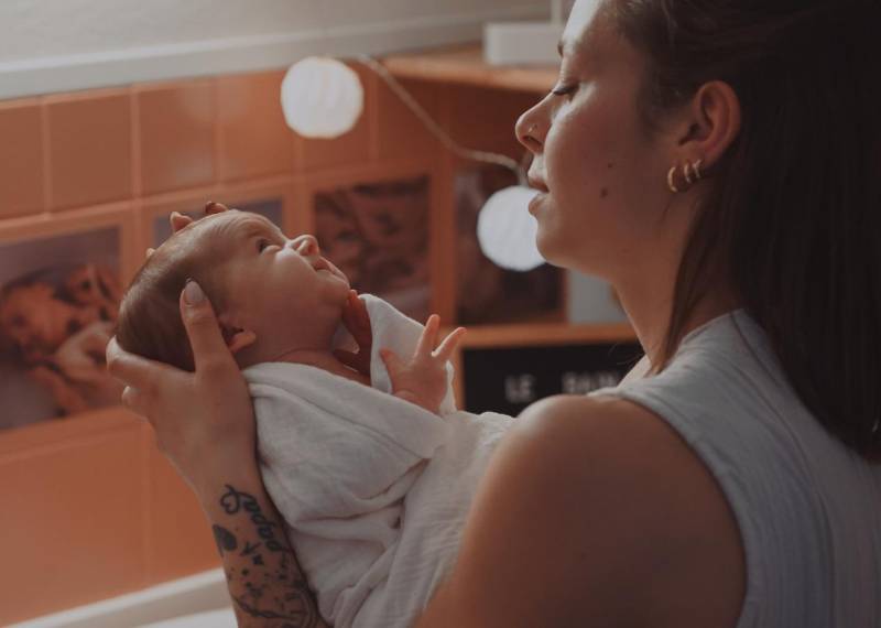 visuel Second souffle, jeune femme tenant son bébé. il est emmailloté dans un drap de bain.